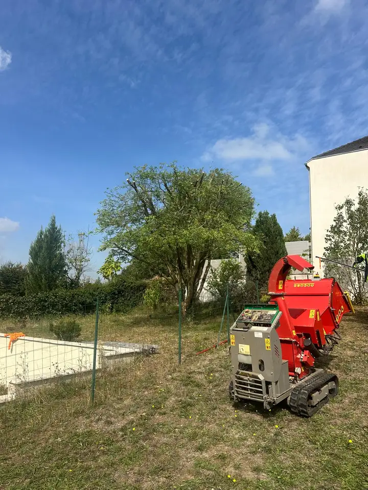 Broyeur de branches rouge dans un jardin près d'un arbre