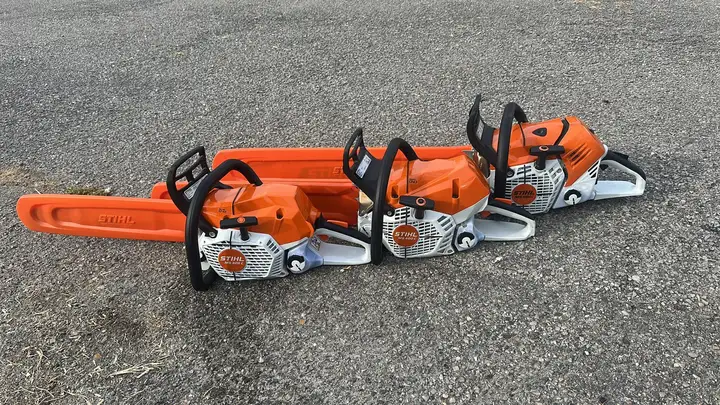 Trois tronçonneuses orange posées au sol